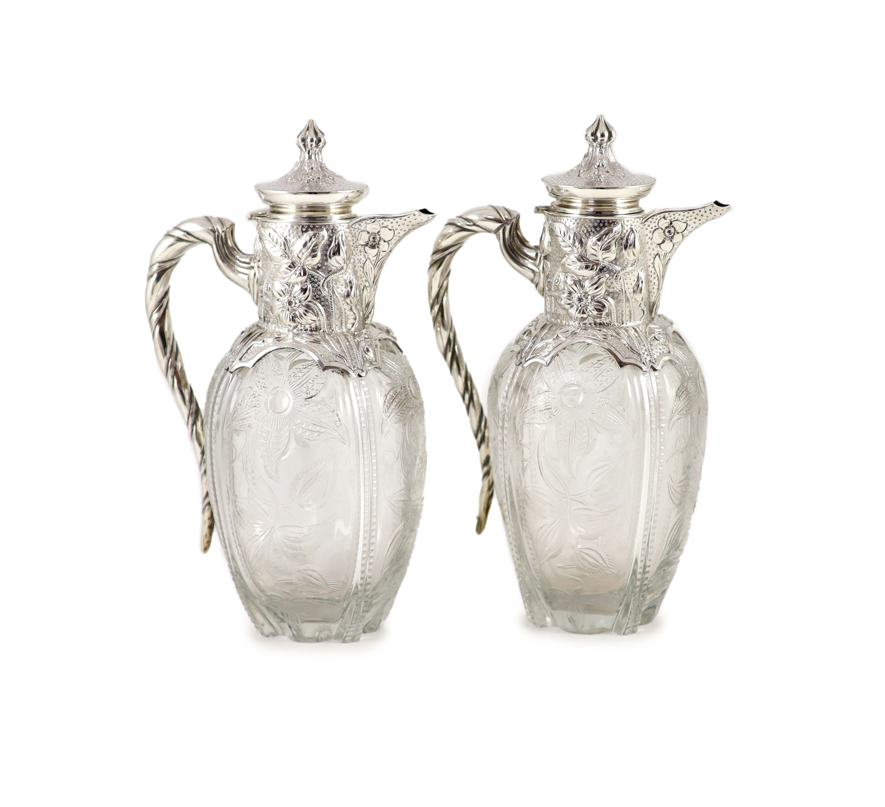 A good pair of late Victorian silver mounted ‘rock crystal’ glass claret jugs, with hinged covers, by John Grinsell & Sons